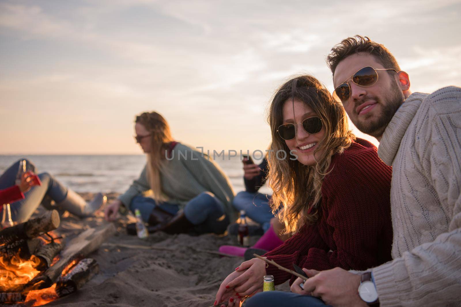 Couple enjoying with friends at sunset on the beach by dotshock