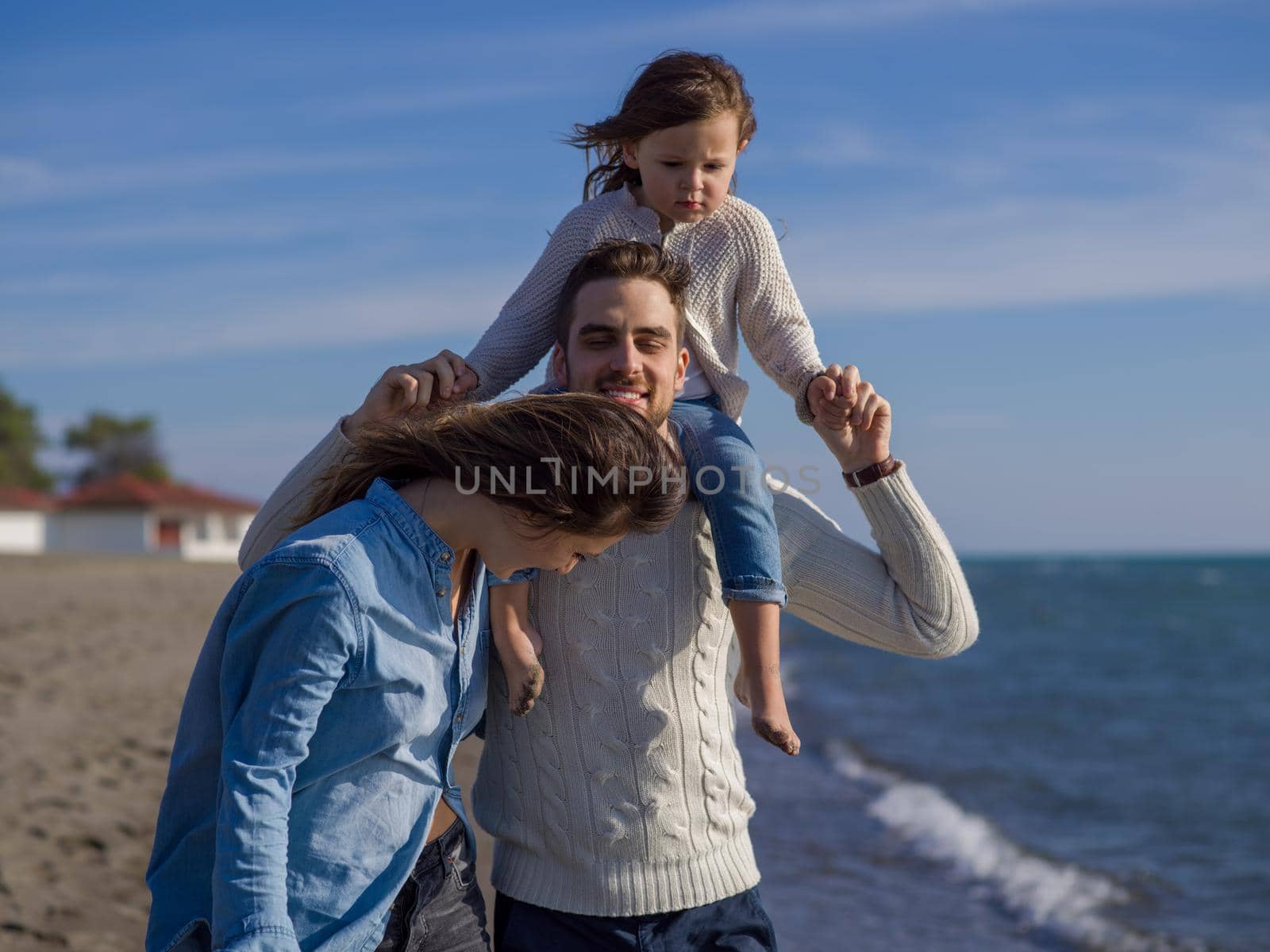 Family with little daughter resting and having fun at beach during autumn day