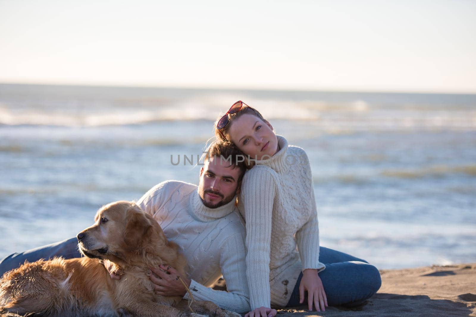 Couple With A Dog enjoying time  together On The Beach at autumn day