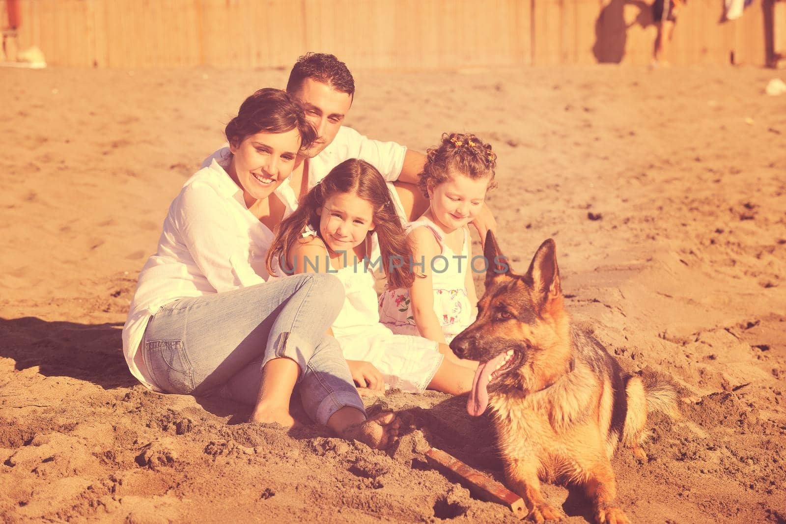 happy young family in white clothing have fun and play with beautiful dog at vacations on beautiful beach 