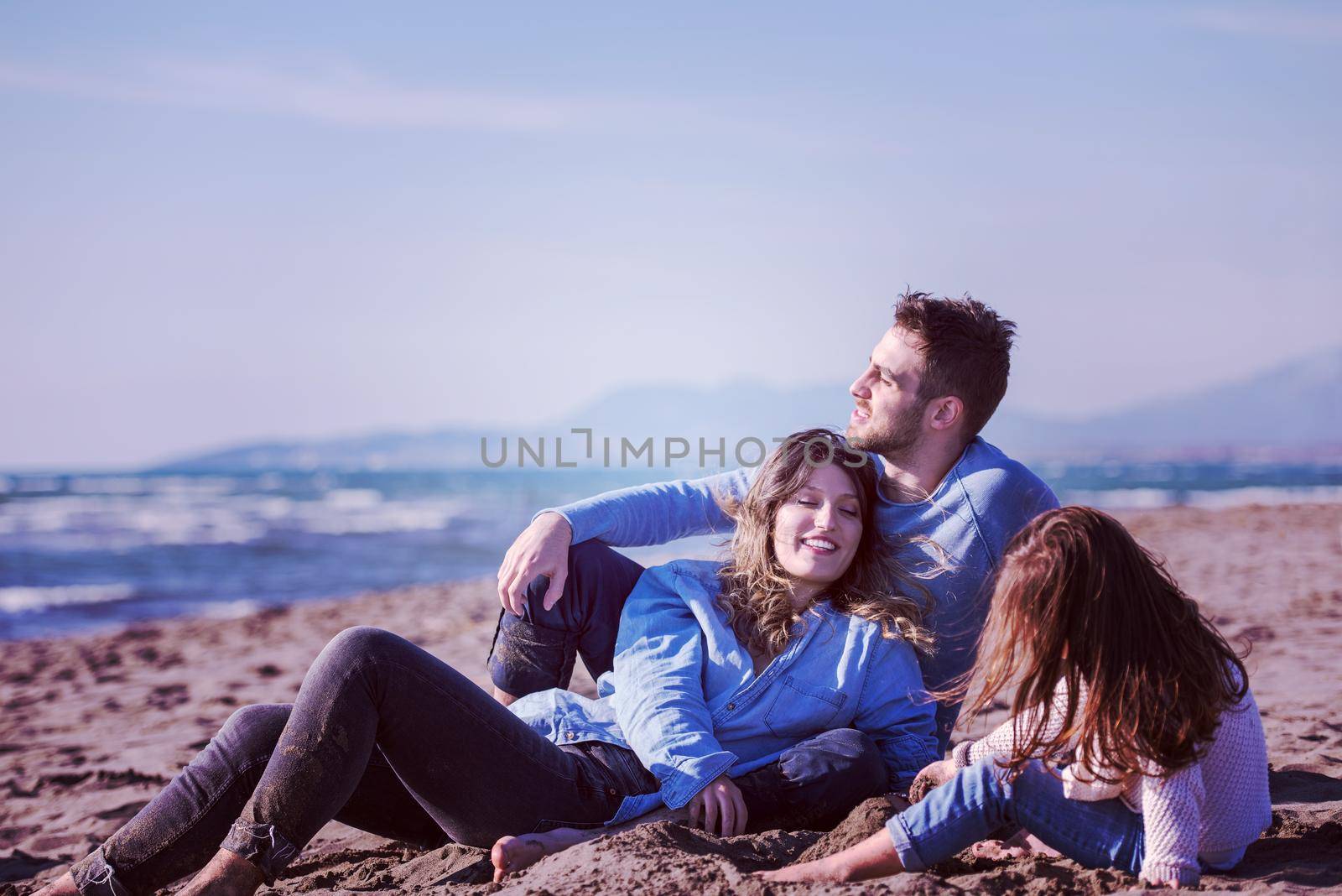 Family with kids resting and having fun at beach during autumn day filter