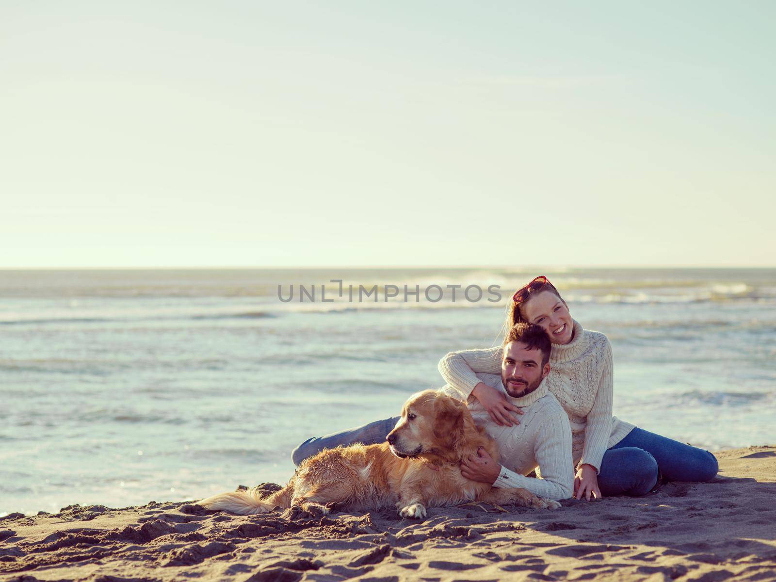 Couple With A Dog enjoying time  together On The Beach at autumn day colored filter