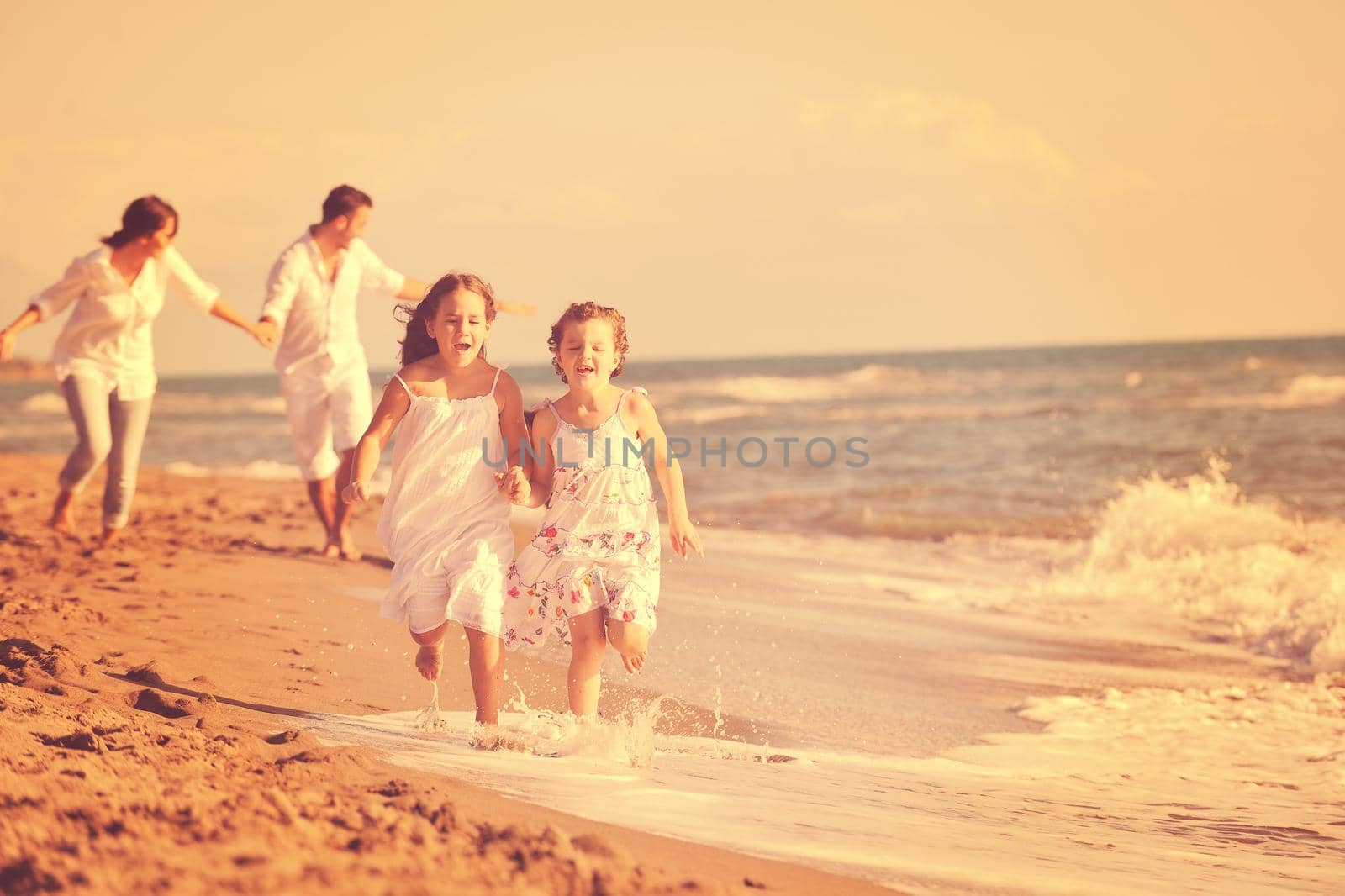 happy young family in white clothing have fun and play with beautiful dog at vacations on beautiful beach 