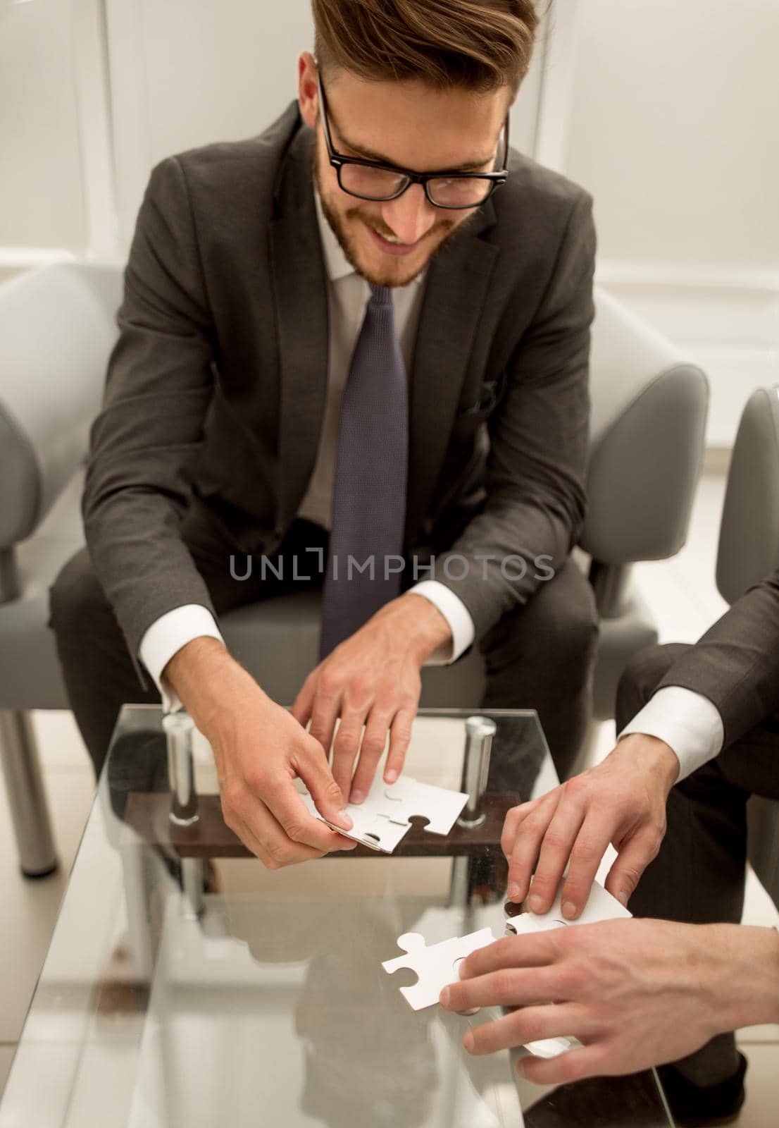 close up.business colleagues putting together a puzzle ,sitting at office Desk.the concept of cooperation