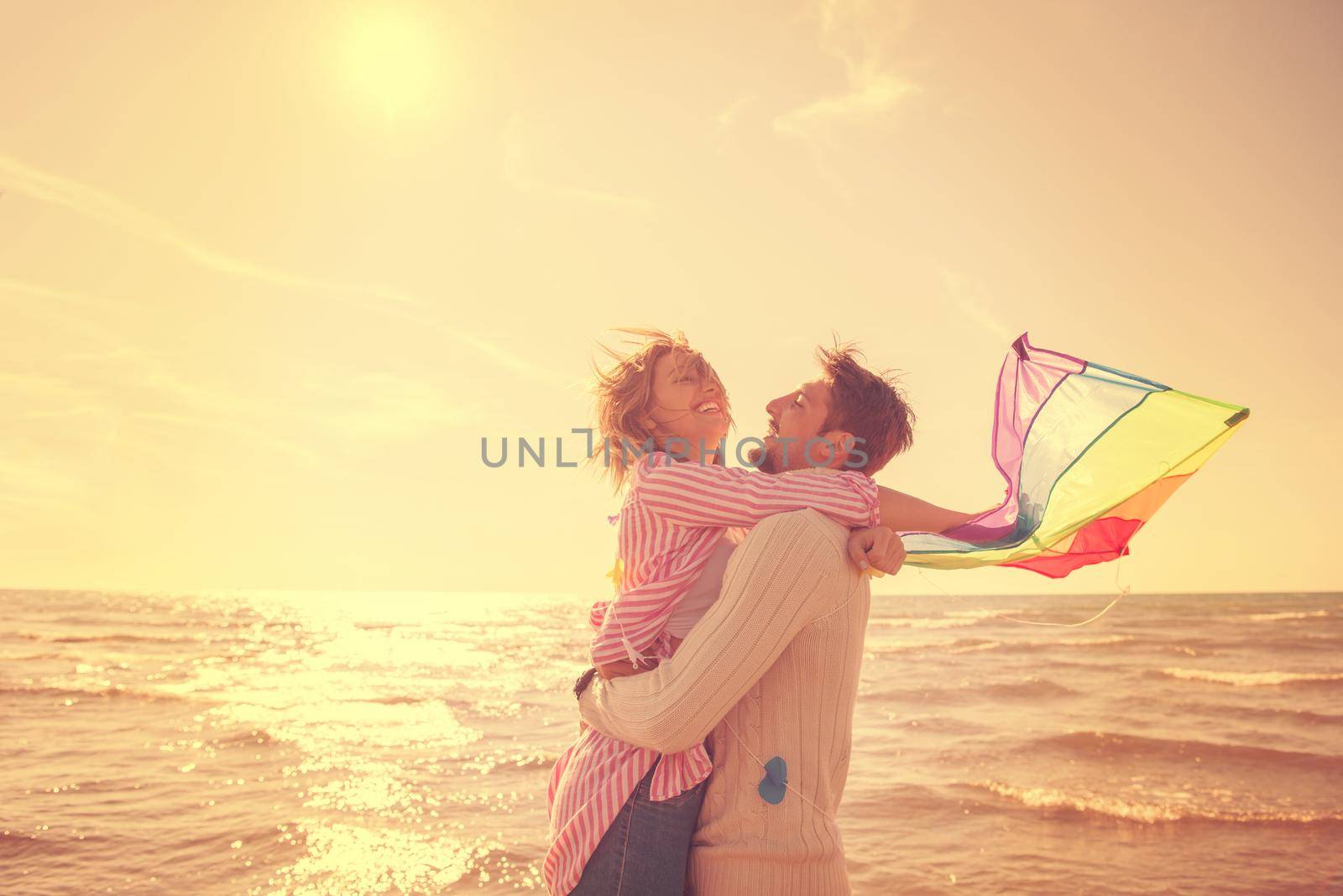 Young Couple having fun and Playing With A Kite On The Beach at autumn day filter