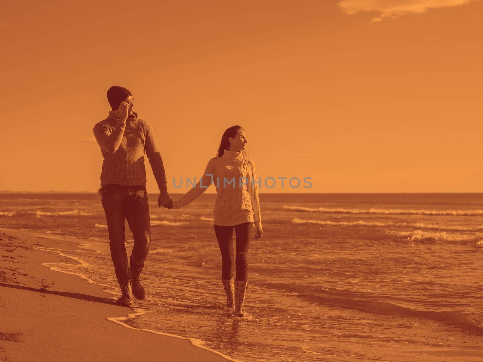 Young couple having fun walking and hugging on beach during autumn sunny day