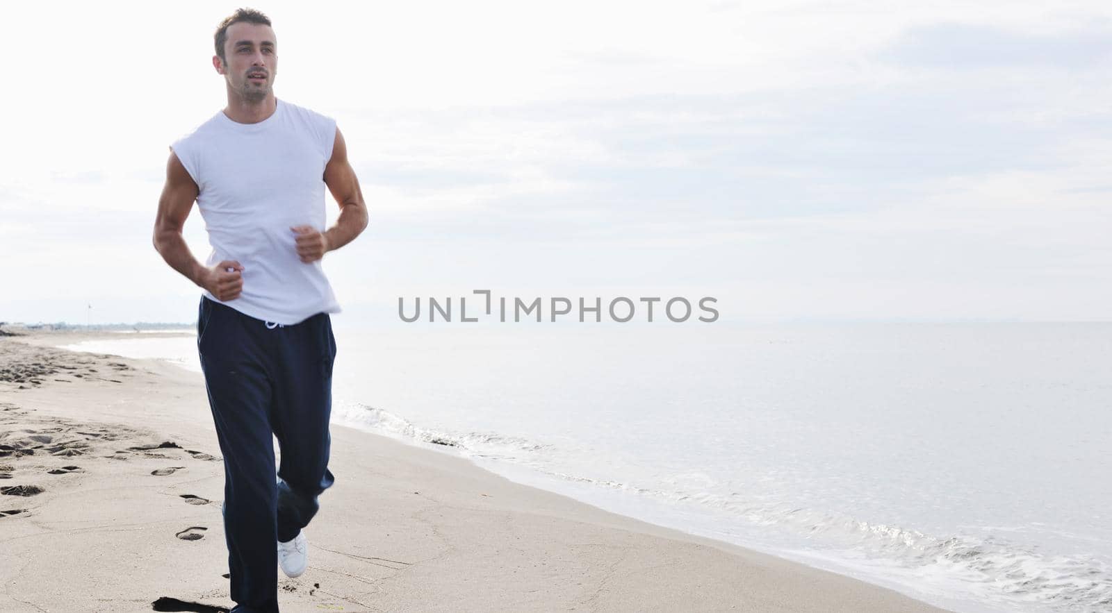 young man running and jogging at early morning on beach