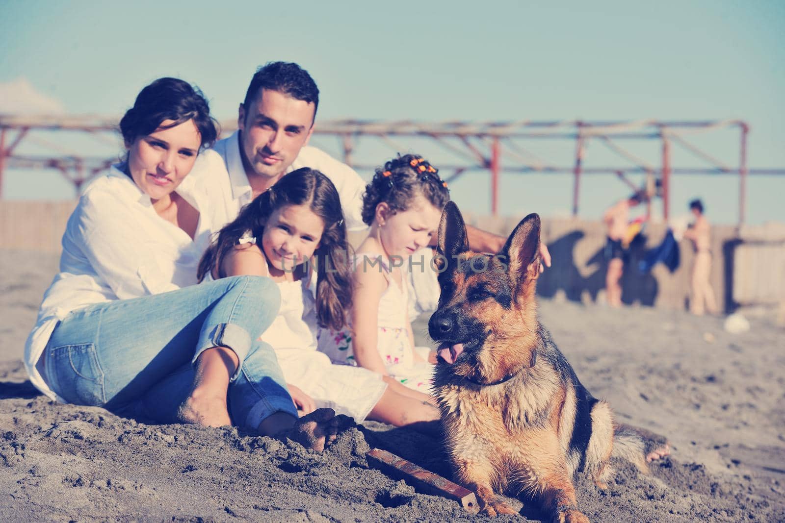 happy young family in white clothing have fun and play with beautiful dog at vacations on beautiful beach 