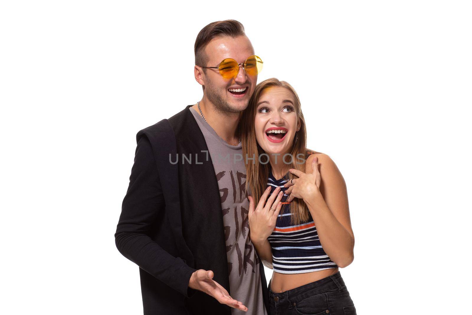 Happy young lovely couple standing together and laughing. Studio shot over white background. by nazarovsergey