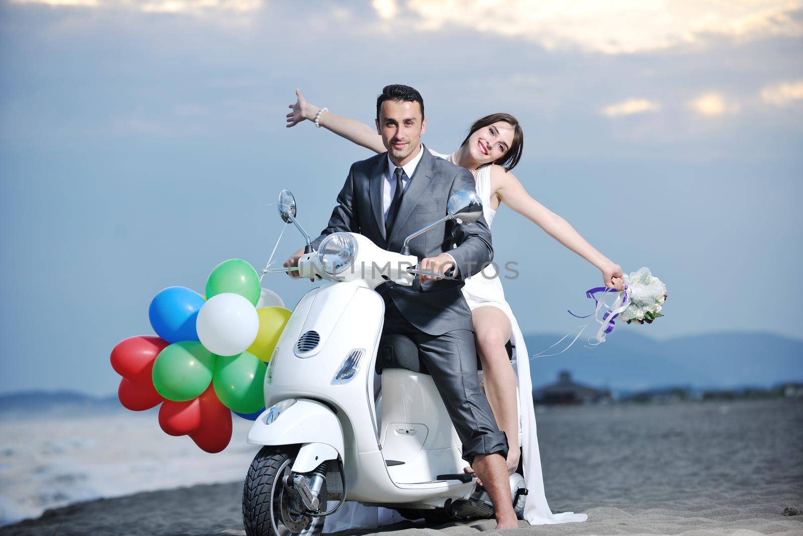 just married couple on the beach ride white scooter by dotshock