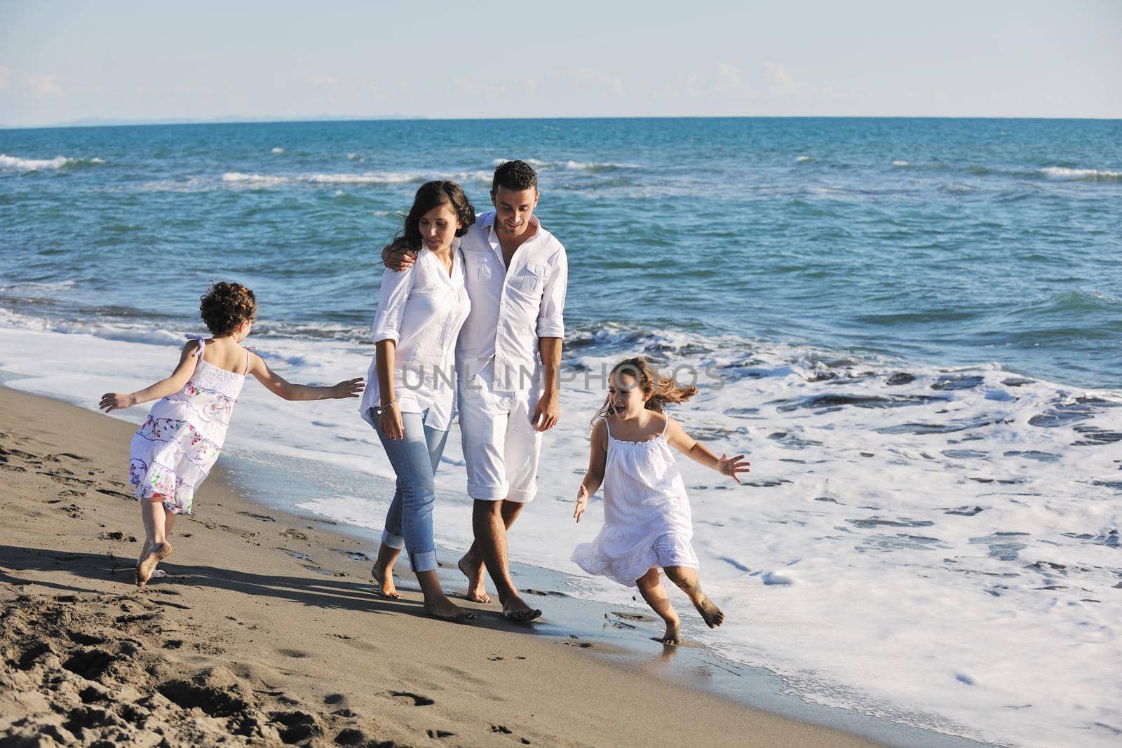 happy young family in white clothing have fun at vacations on beautiful beach