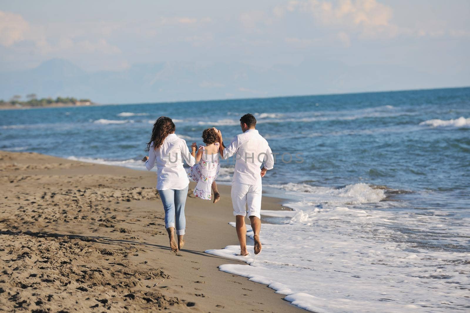 happy young family in white clothing have fun at vacations on beautiful beach