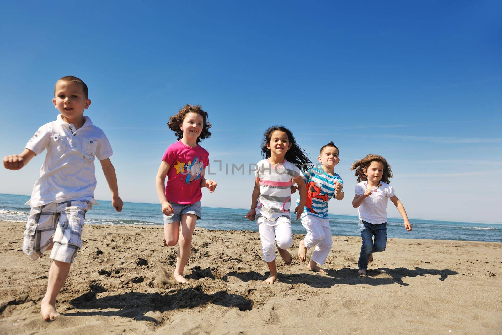 group of happy child on beach who have fun and play games