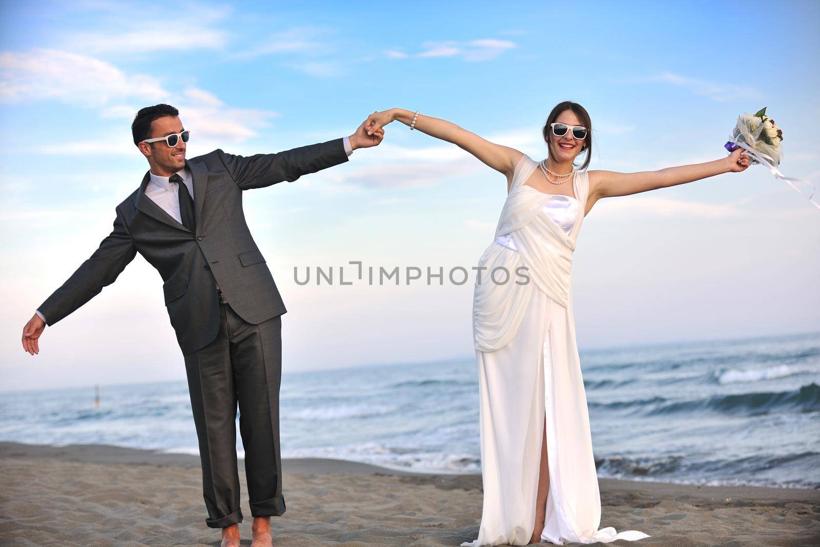 happy just married young couple celebrating and have fun at beautiful beach sunset