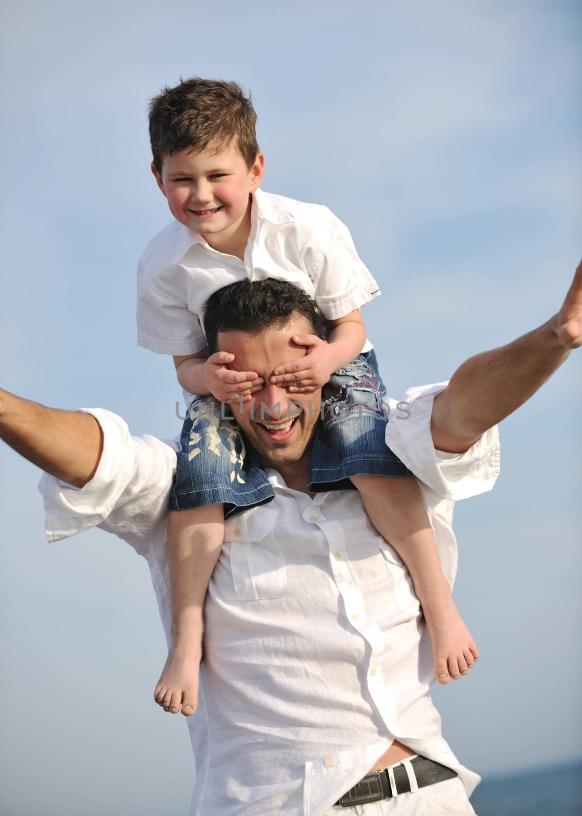 happy father and son have fun and enjoy time on beach by dotshock