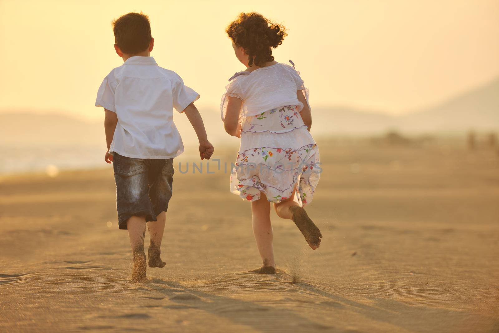 happy young family have fun on beach run and jump  at sunset