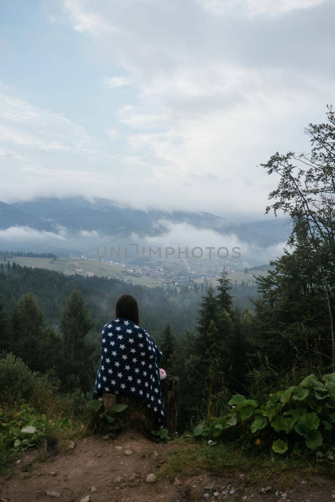 Woman on top of a hill, against the background of a valley in the fog