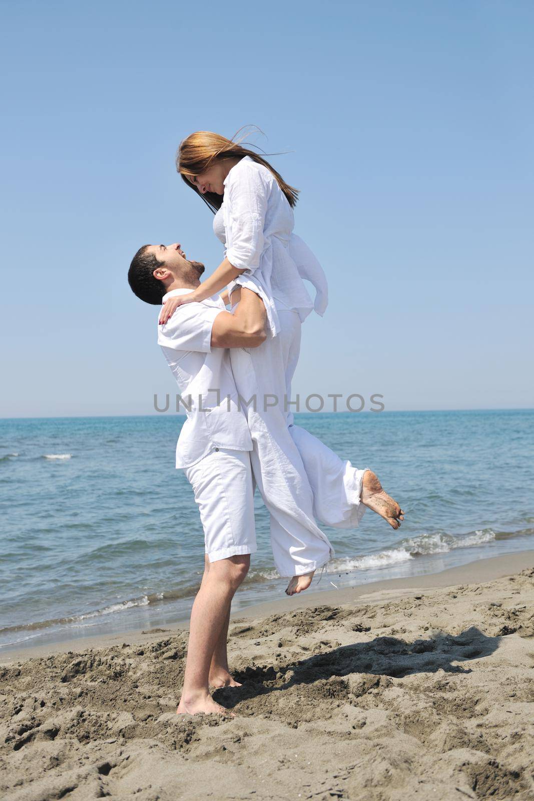 happy young couple have fun on beach by dotshock