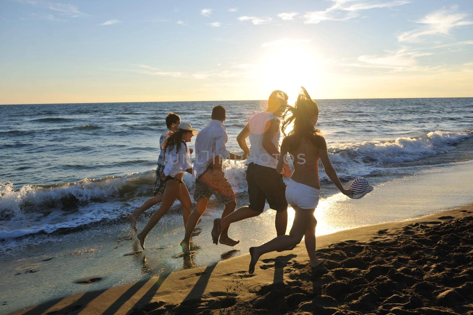 happy young people group have fun white running and jumping on beacz at sunset time