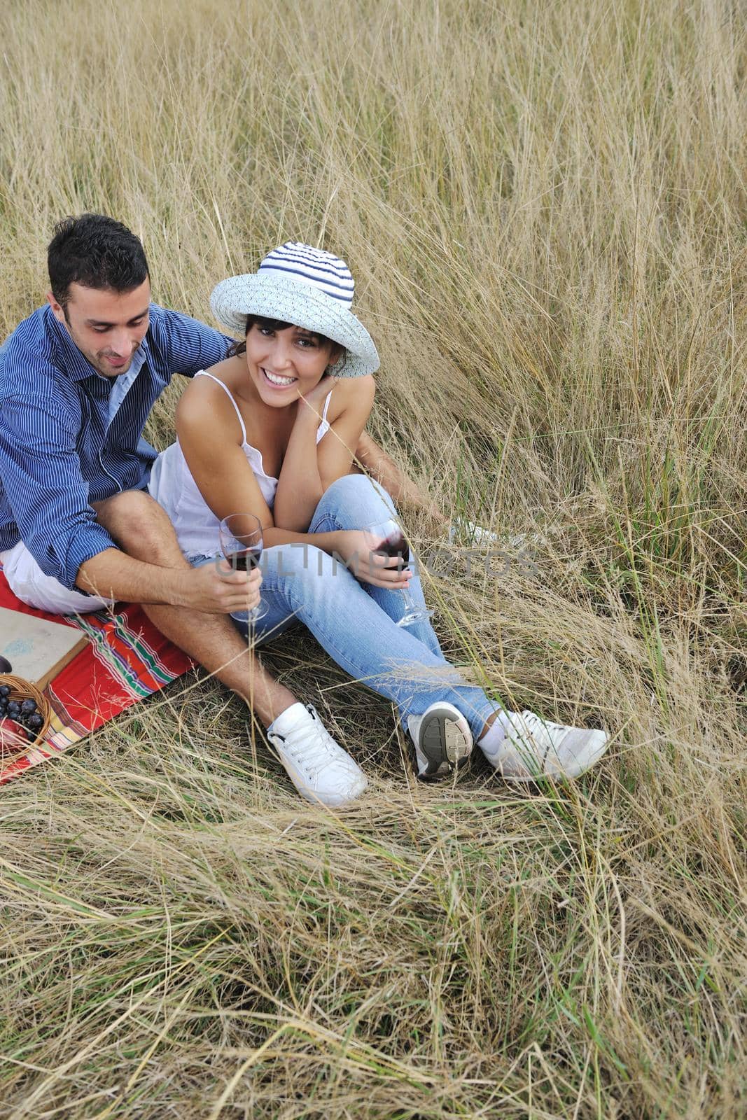 happy couple enjoying countryside picnic in long grass by dotshock