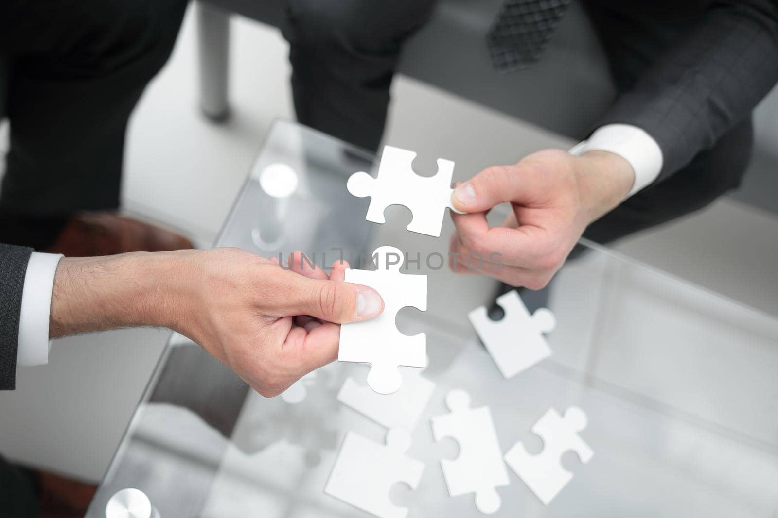 close up.business partners hold the puzzle pieces while sitting at their Desk