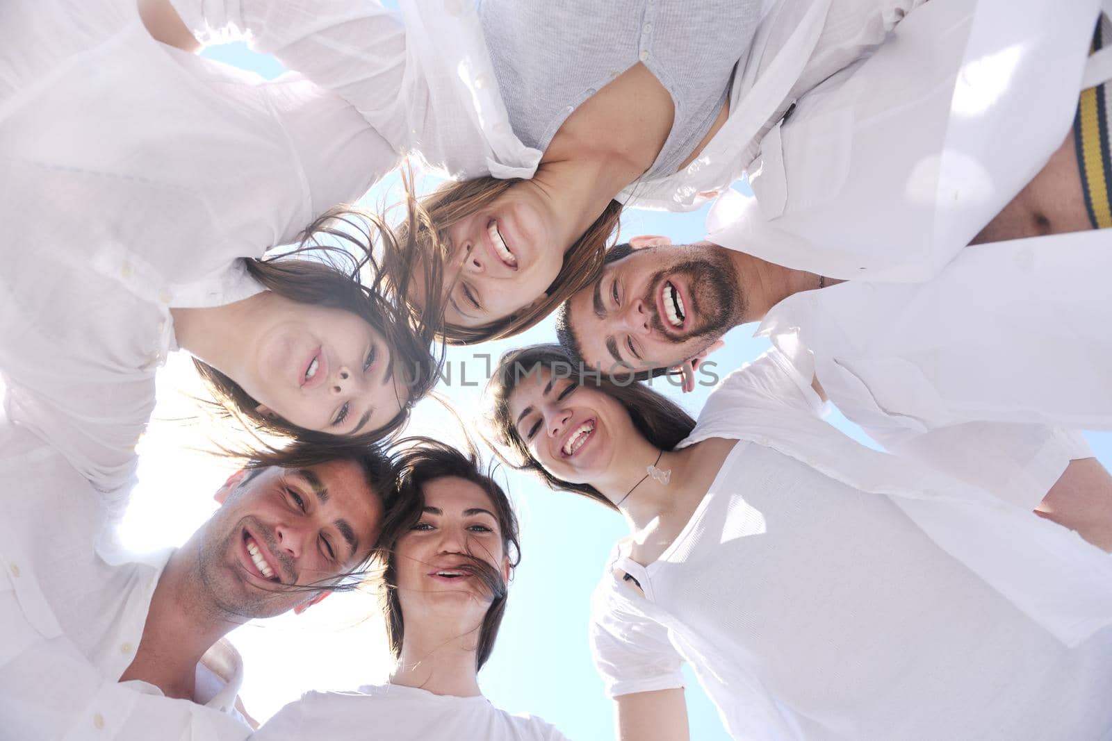 Group of happy young people in circle at beach  have fun and smile