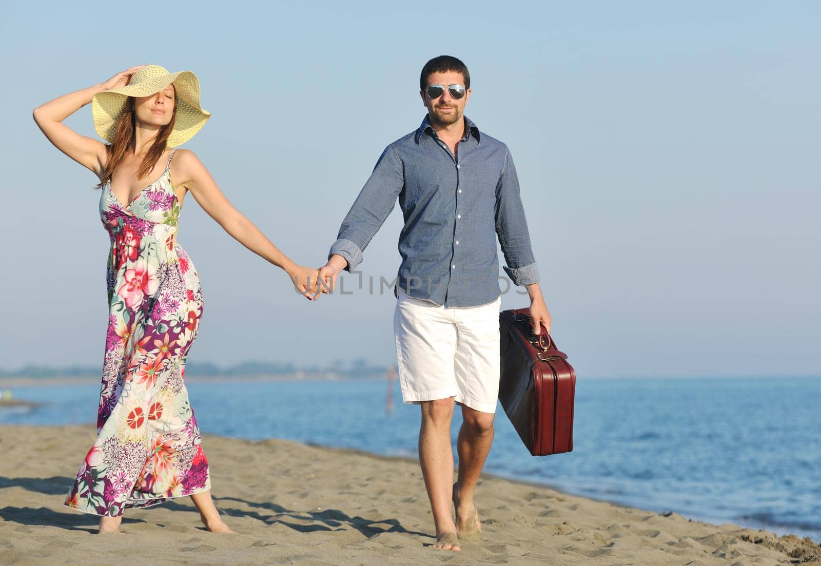 couple on beach with travel bag representing freedom and funy honeymoon concept