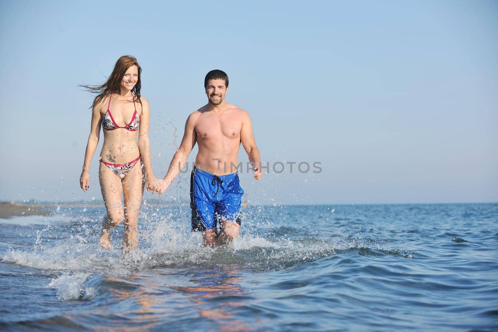 happy young couple have romantic time on beach at sunset