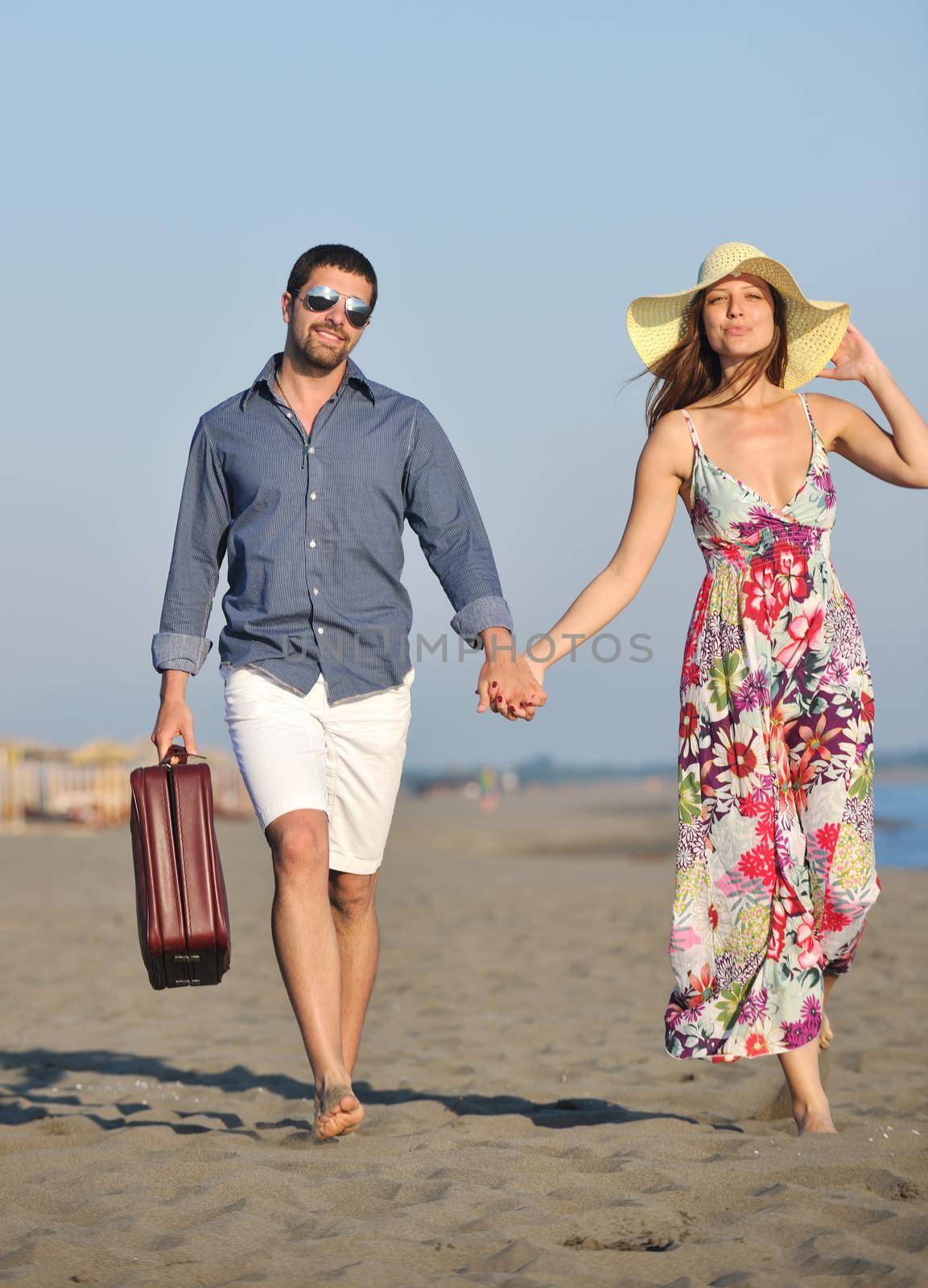 couple on beach with travel bag by dotshock