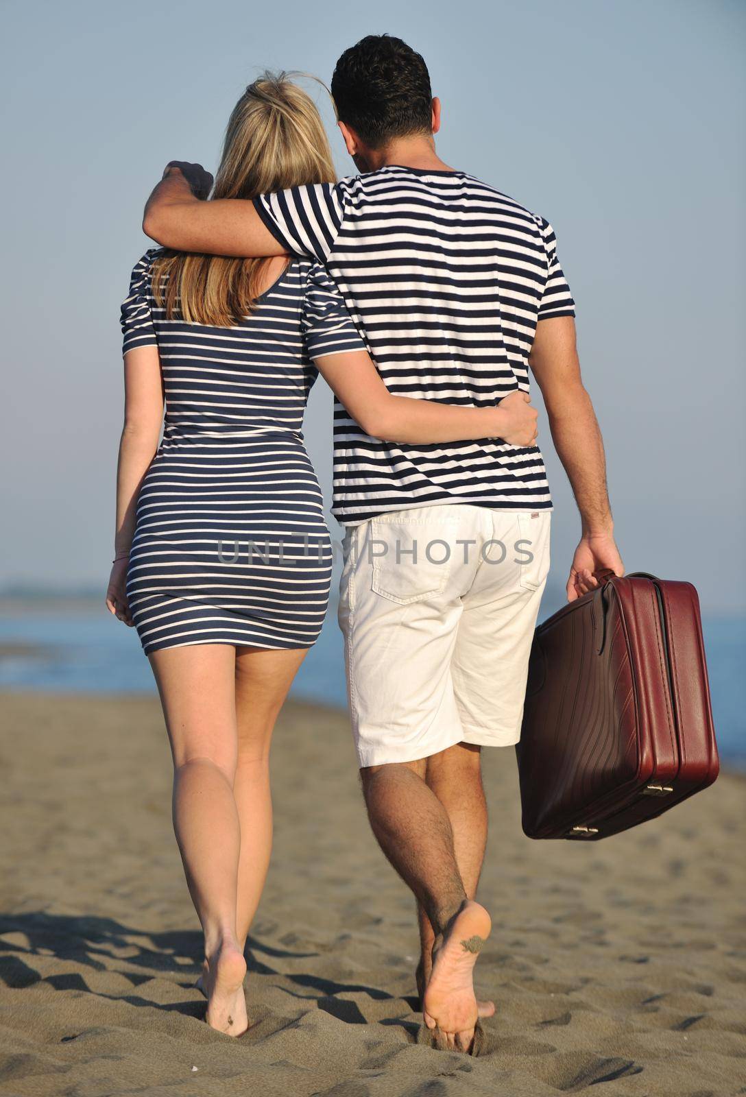 couple on beach with travel bag by dotshock
