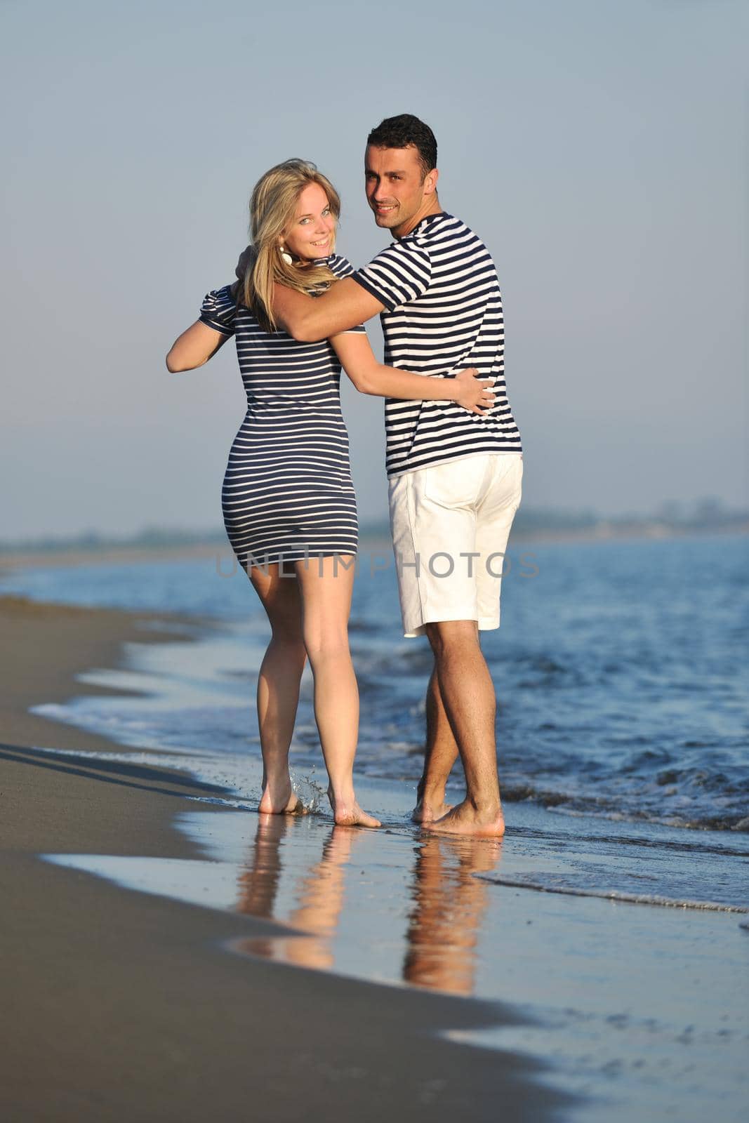 happy young couple have romantic time on beach at sunset