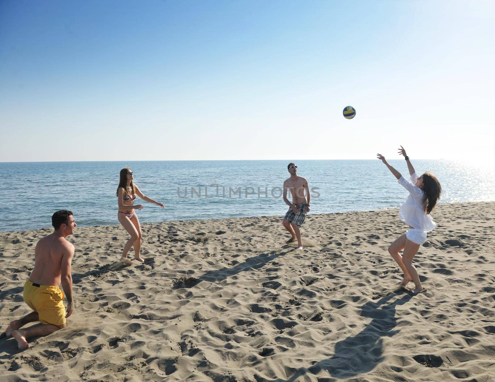 young people group have fun and play beach volleyball by dotshock