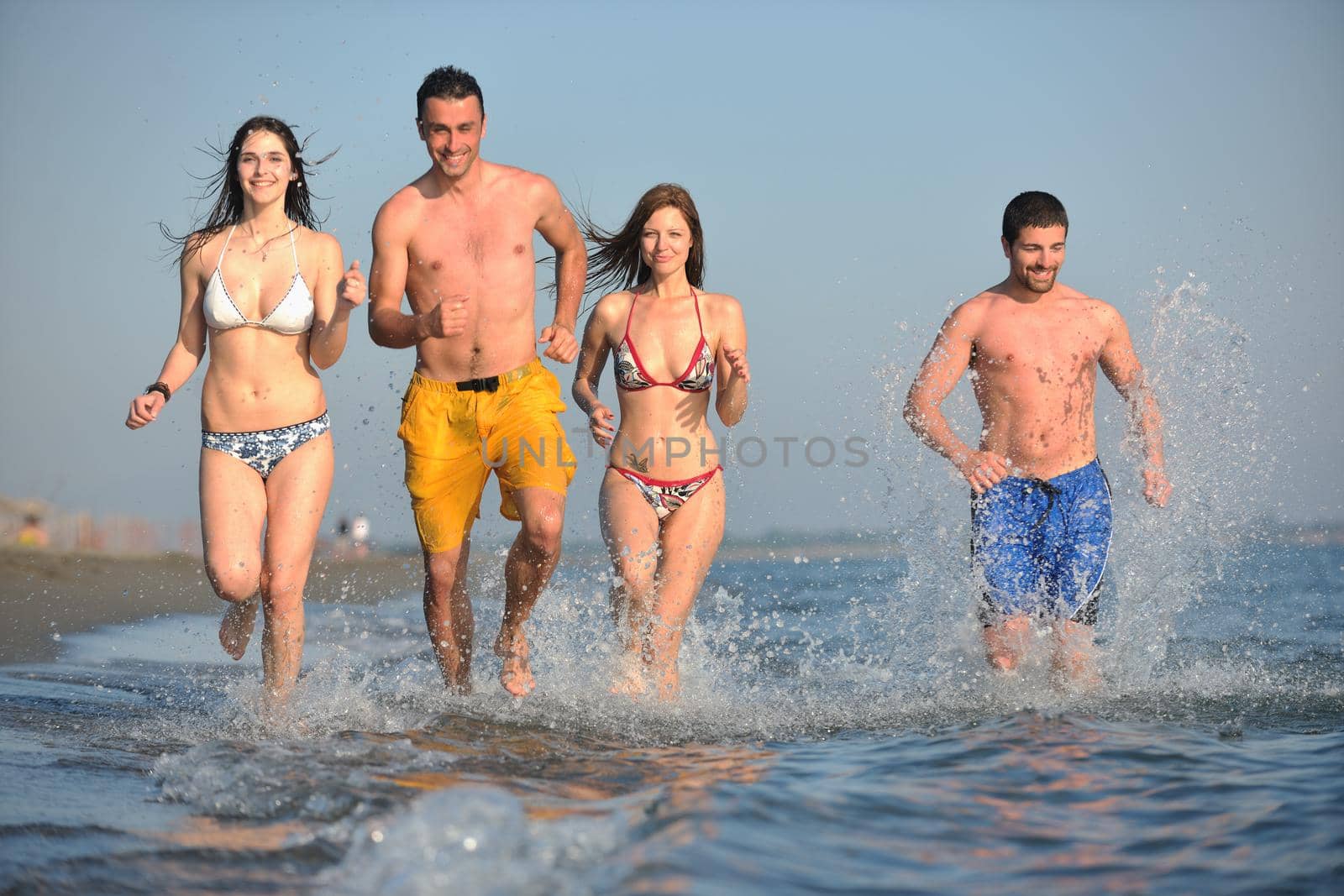 happy people group have fun and running on beach by dotshock