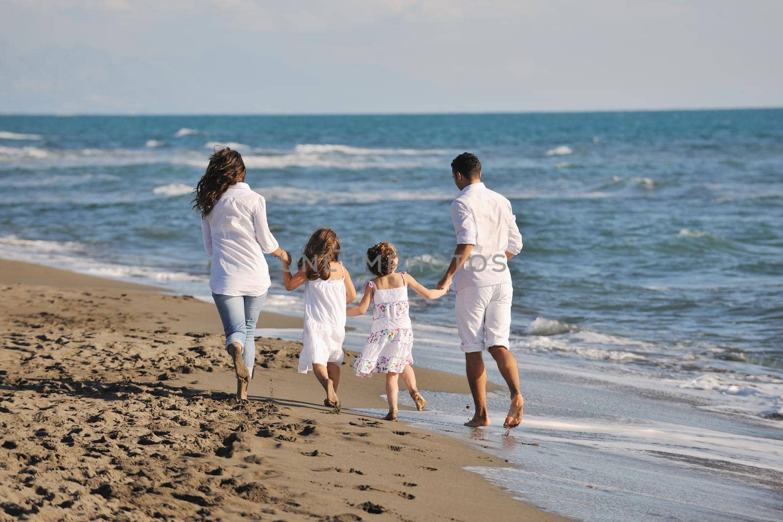 happy young family in white clothing have fun at vacations on beautiful beach 