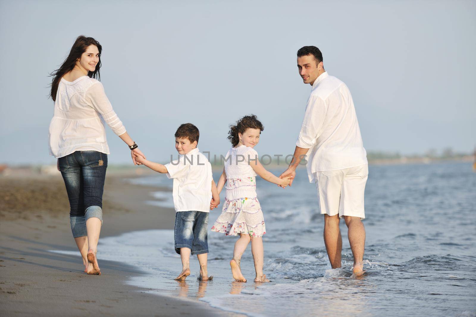 happy young family have fun on beach at sunset by dotshock