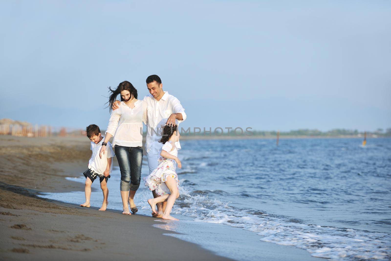 happy young family have fun on beach run and jump  at sunset