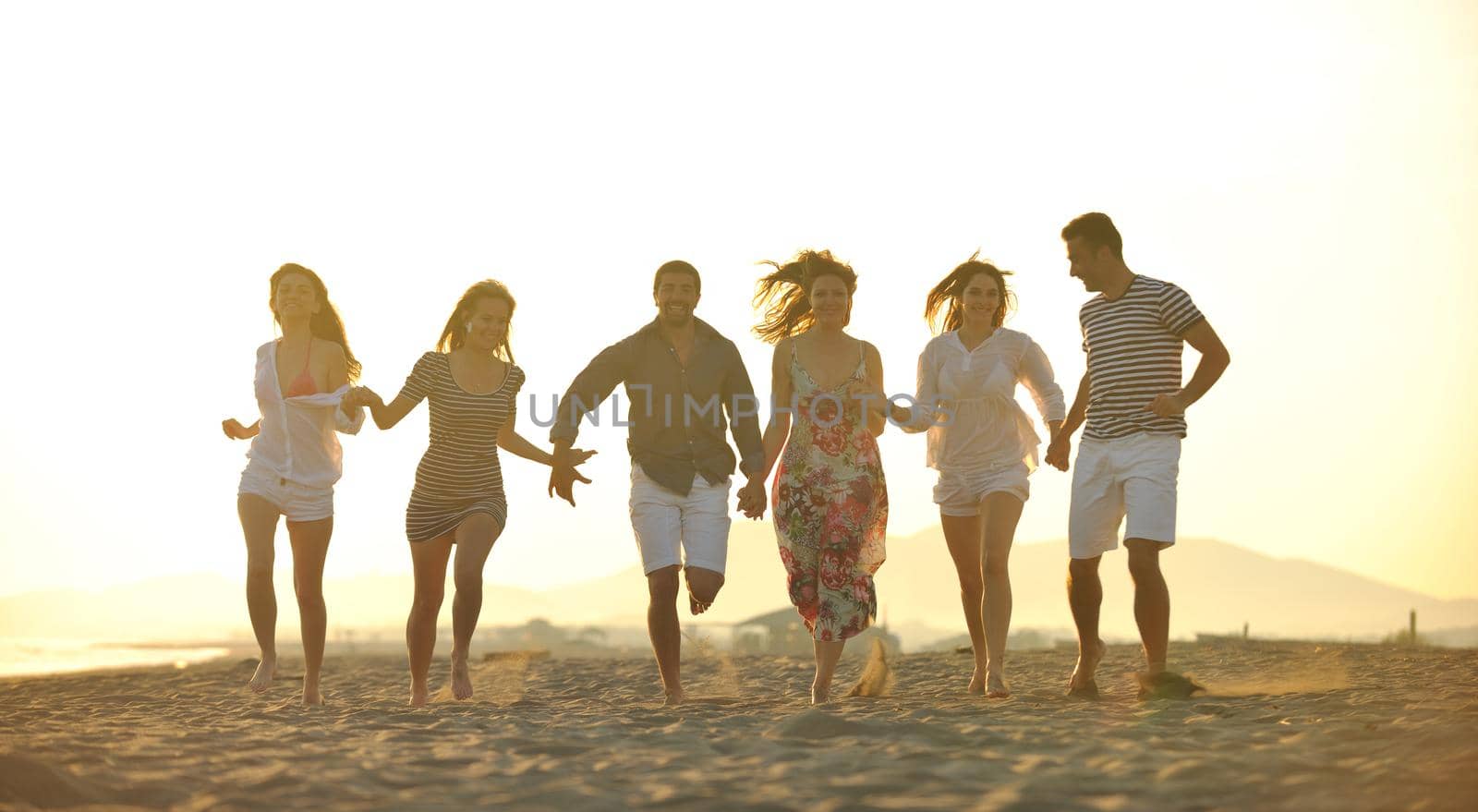 happy young  people group have fun on beach by dotshock