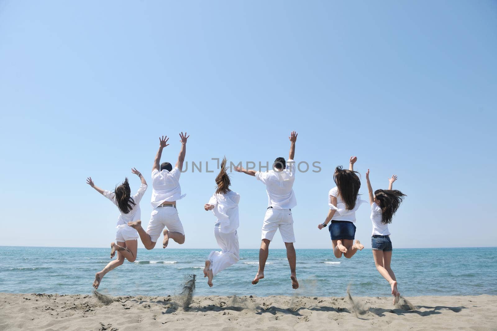 happy people group have fun and running on beach by dotshock