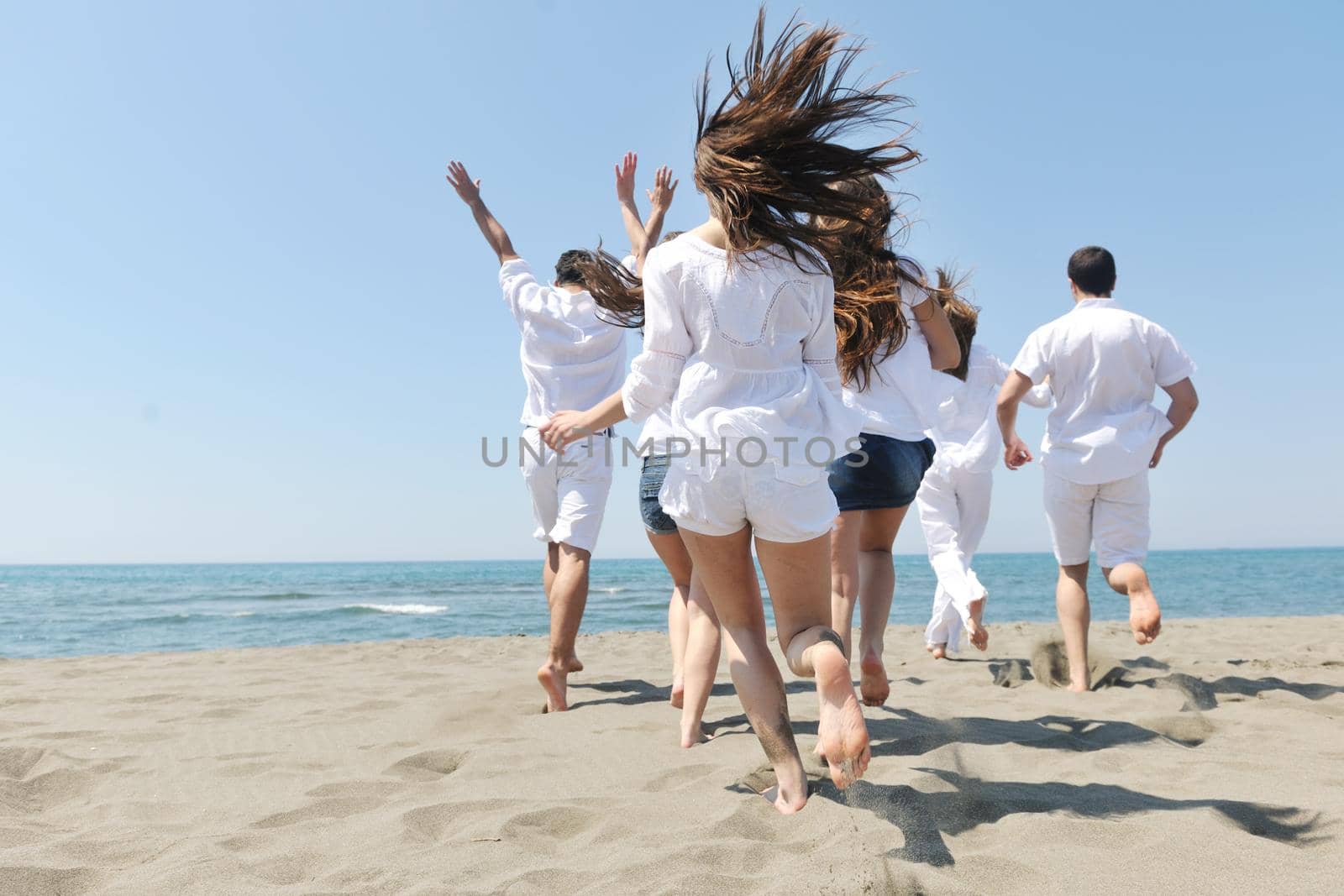 happy people group have fun and running on beach by dotshock