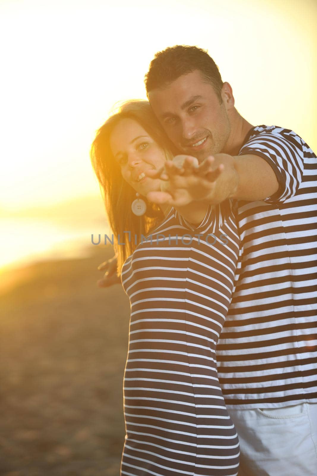 happy young couple have romantic time on beach at sunset