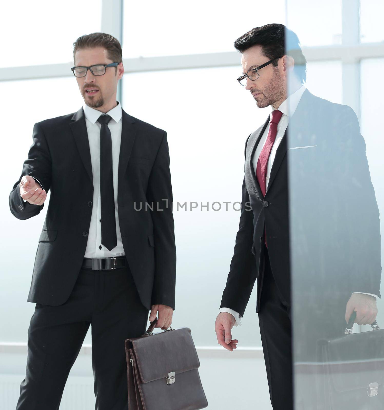 Unrecognizable businessmen walking with a portfolio in a modern office