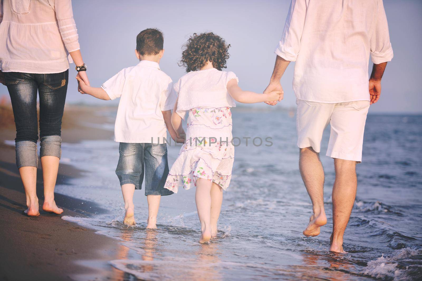 happy young family have fun on beach at sunset by dotshock