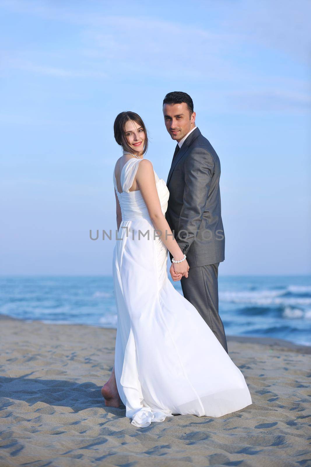 happy just married young couple celebrating and have fun at beautiful beach sunset