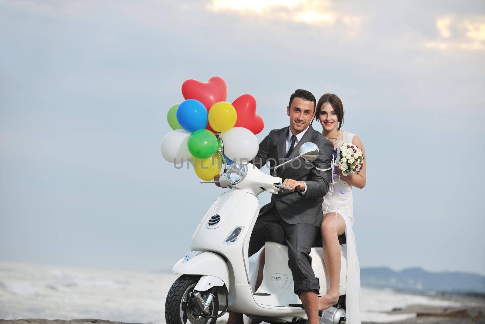 wedding sce of bride and groom just married couple on the beach ride white scooter and have fun