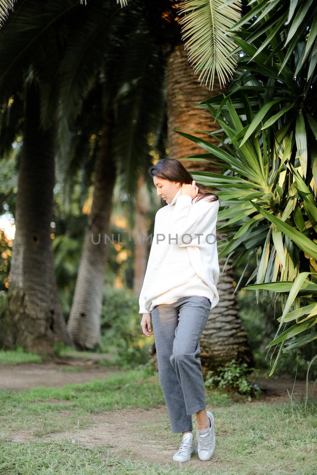 Chinese woman walking in tropical park and standing near palms. by sisterspro