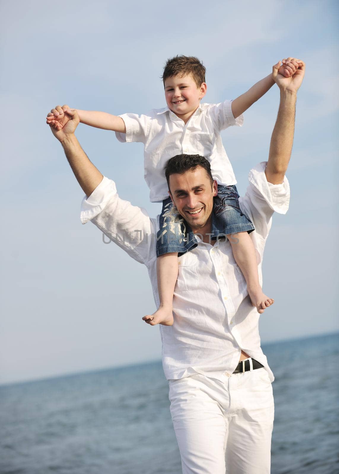 happy father and son have fun and enjoy time on beach by dotshock