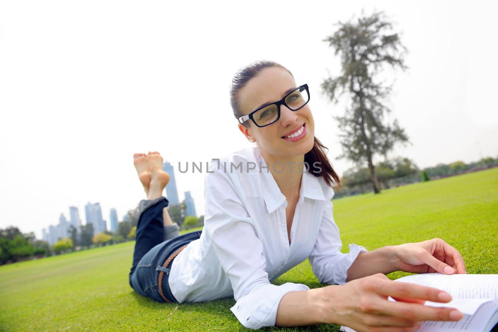 Young woman reading a book in the park by dotshock