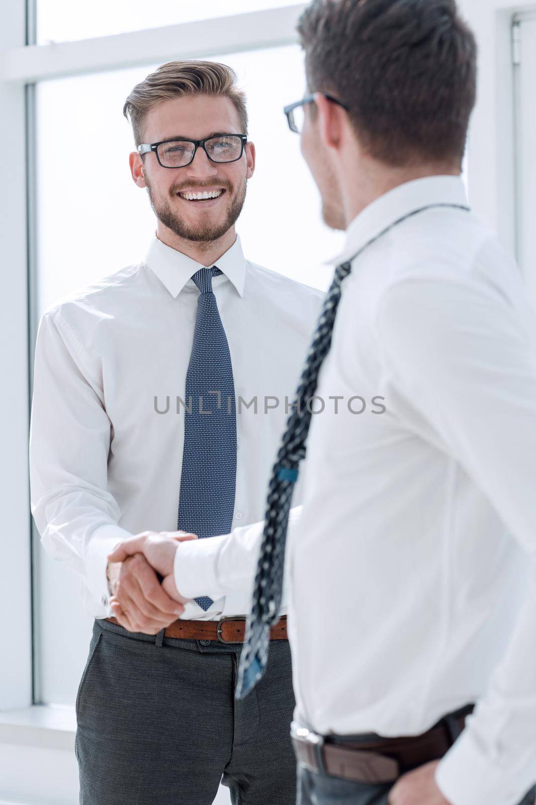 close up.handshake of business partners standing outside an office window. by asdf