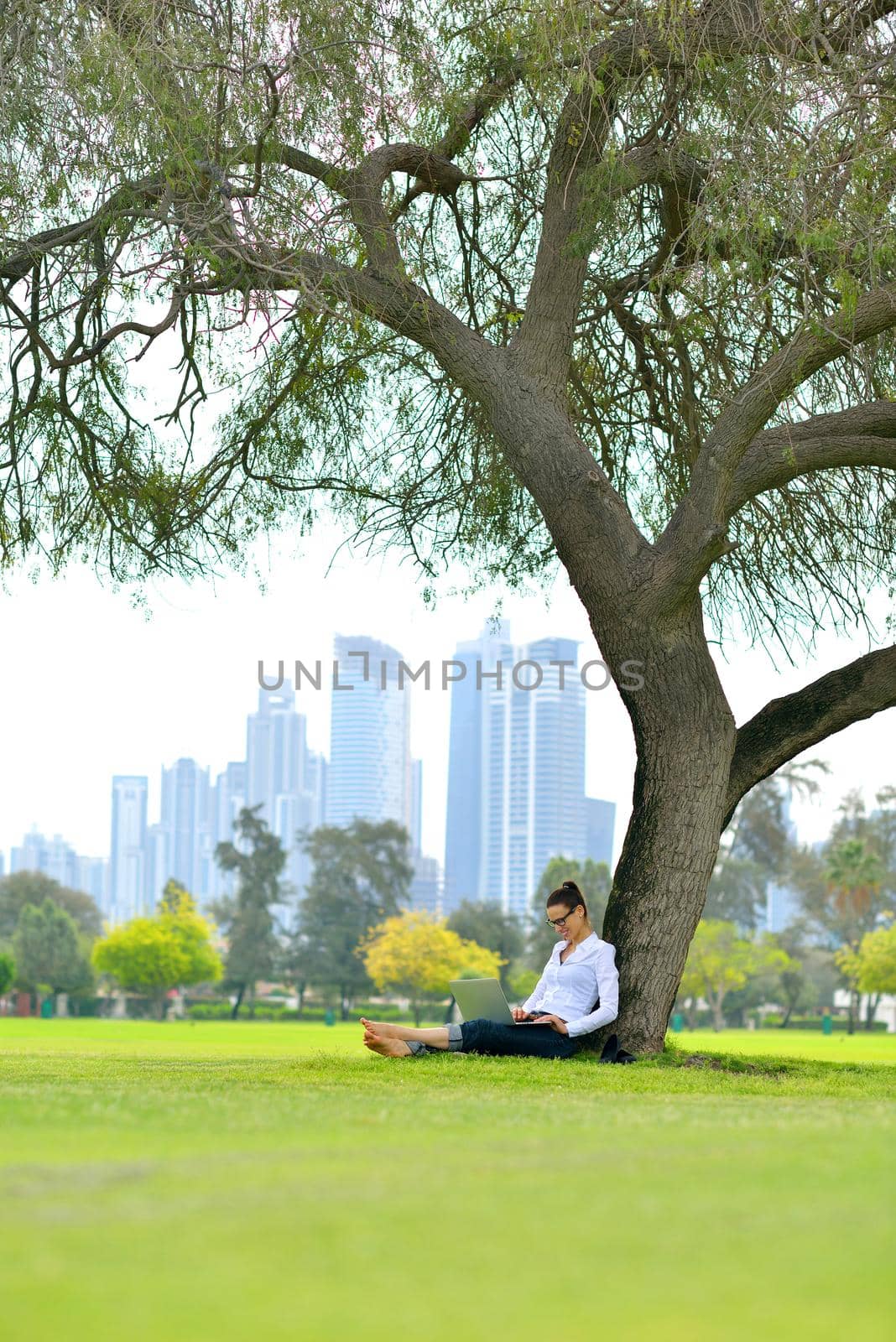 happy young student woman with laptop in city park study