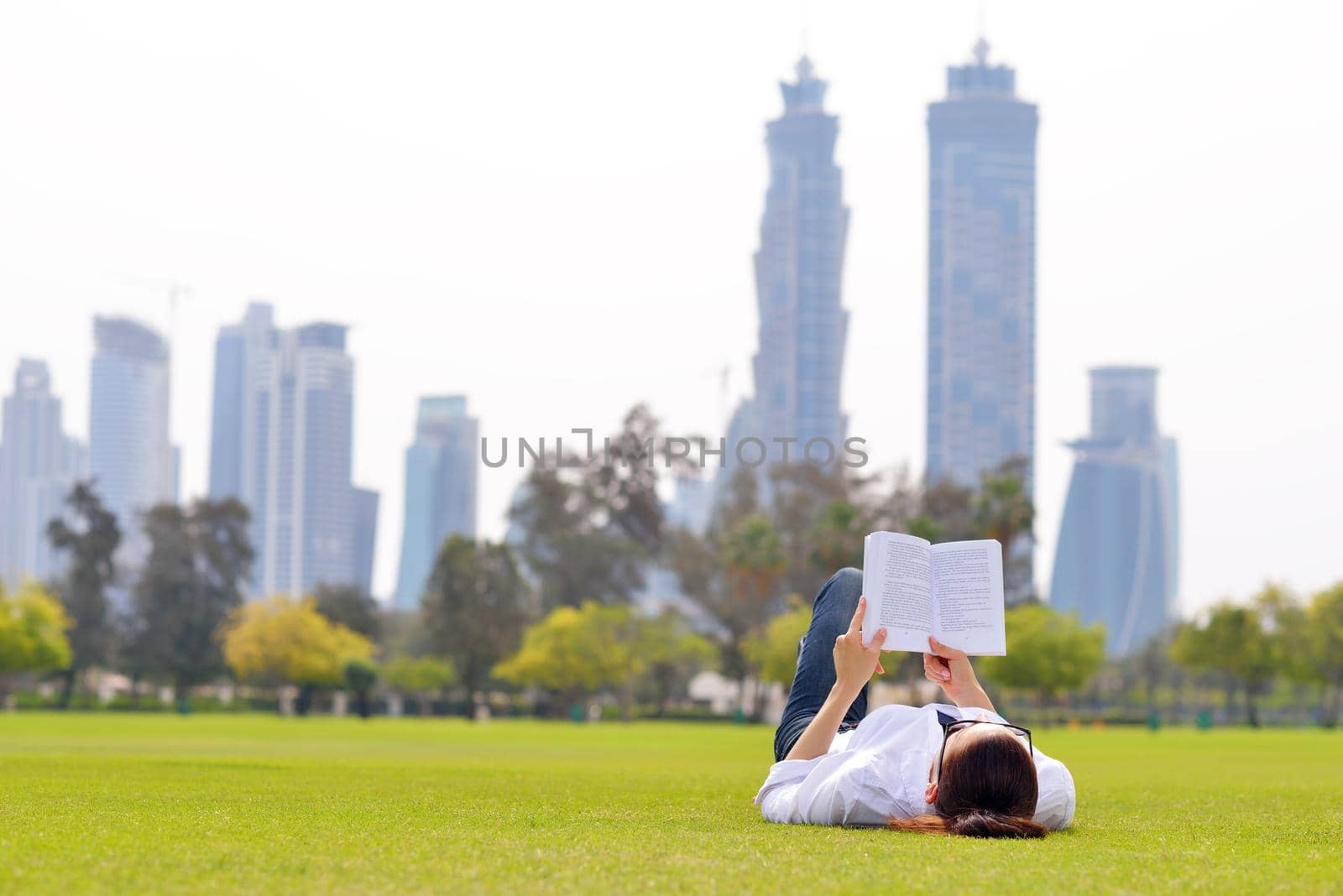 Young woman reading a book in the park by dotshock